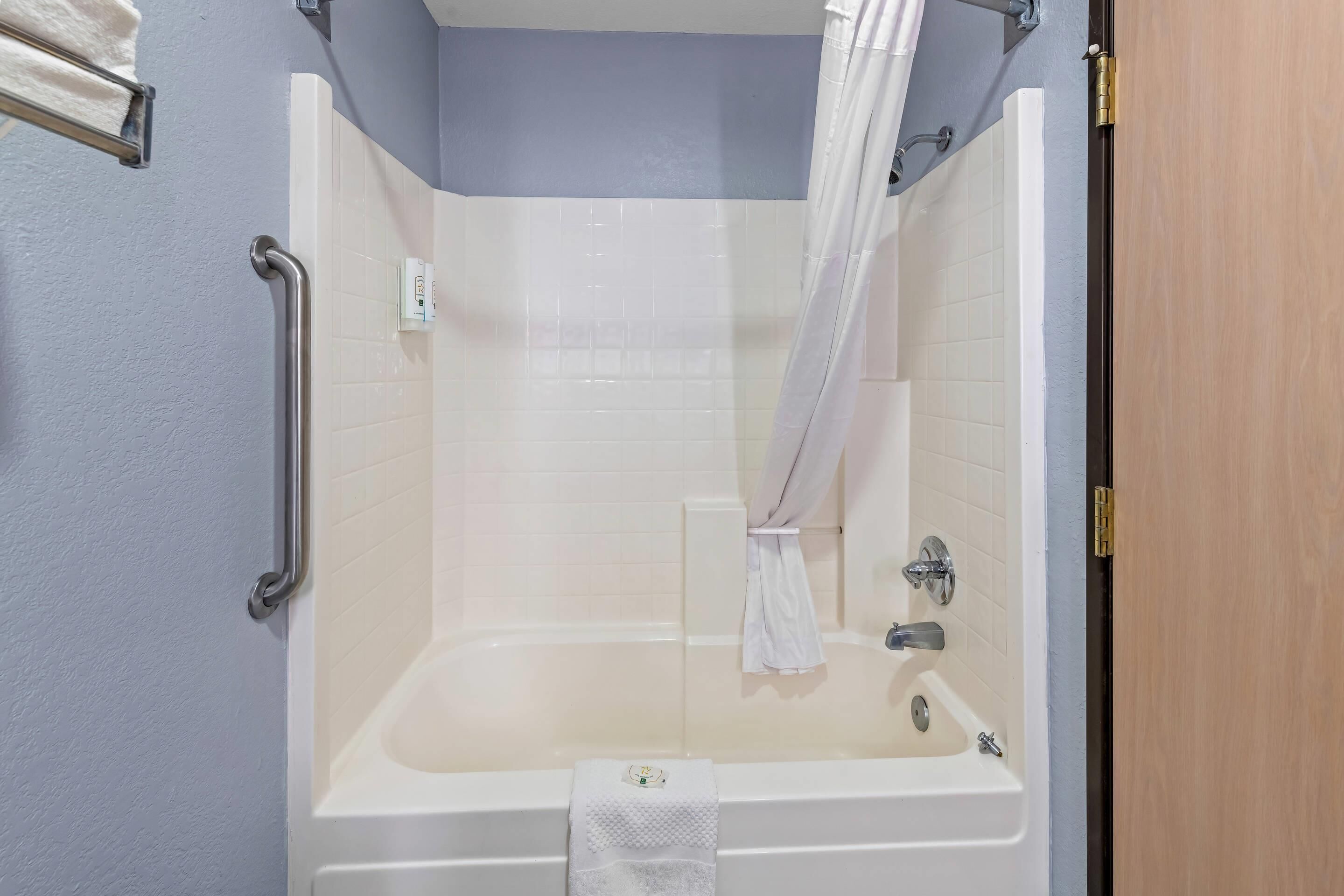 A bathroom with a bathtub, a shower curtain, and a towel rack.