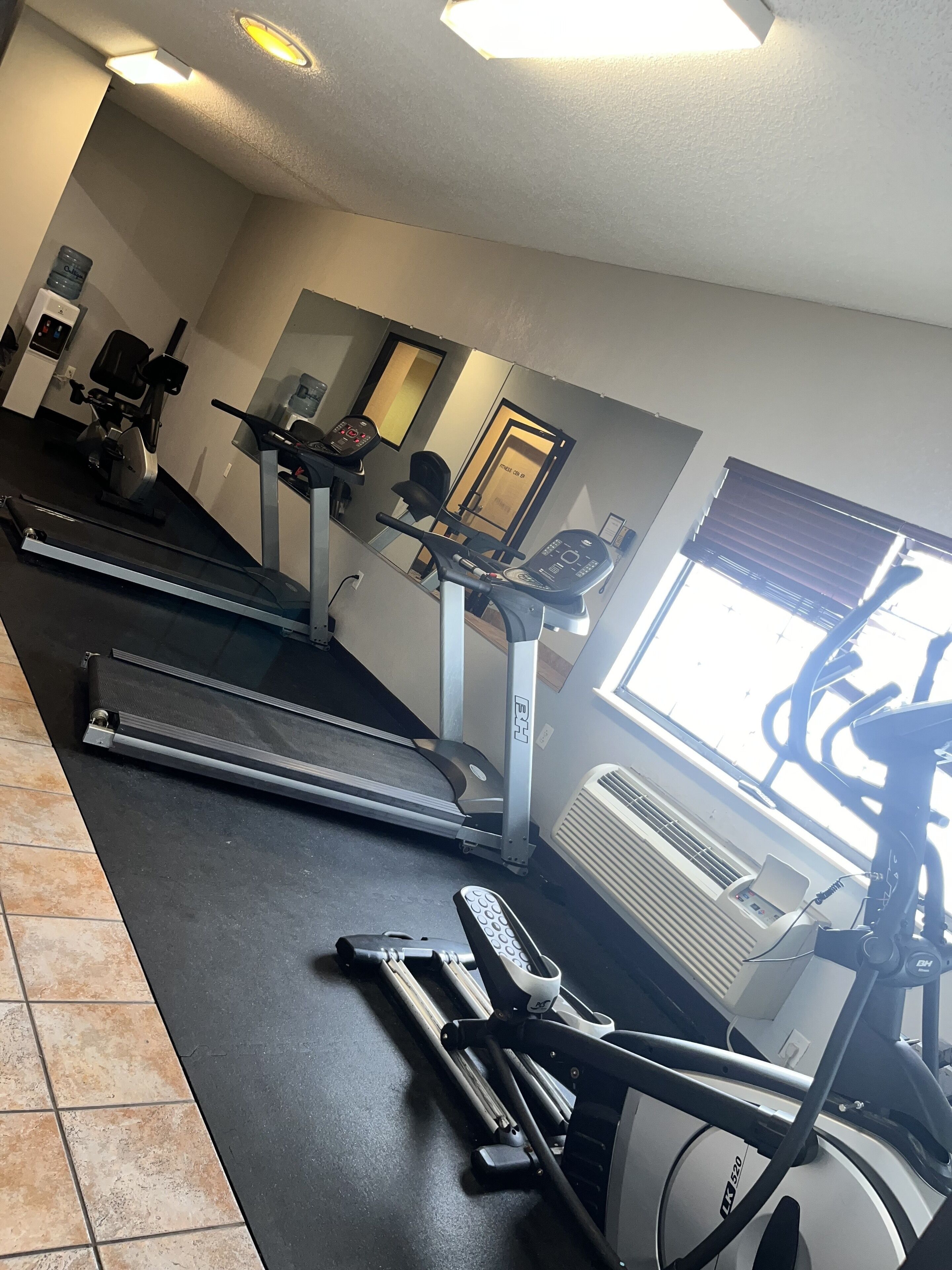A gym with treadmills, elliptical machines, and a stationary bike.