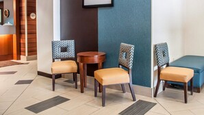 A lobby with a reception desk, two chairs, a round table, and a blue sofa.