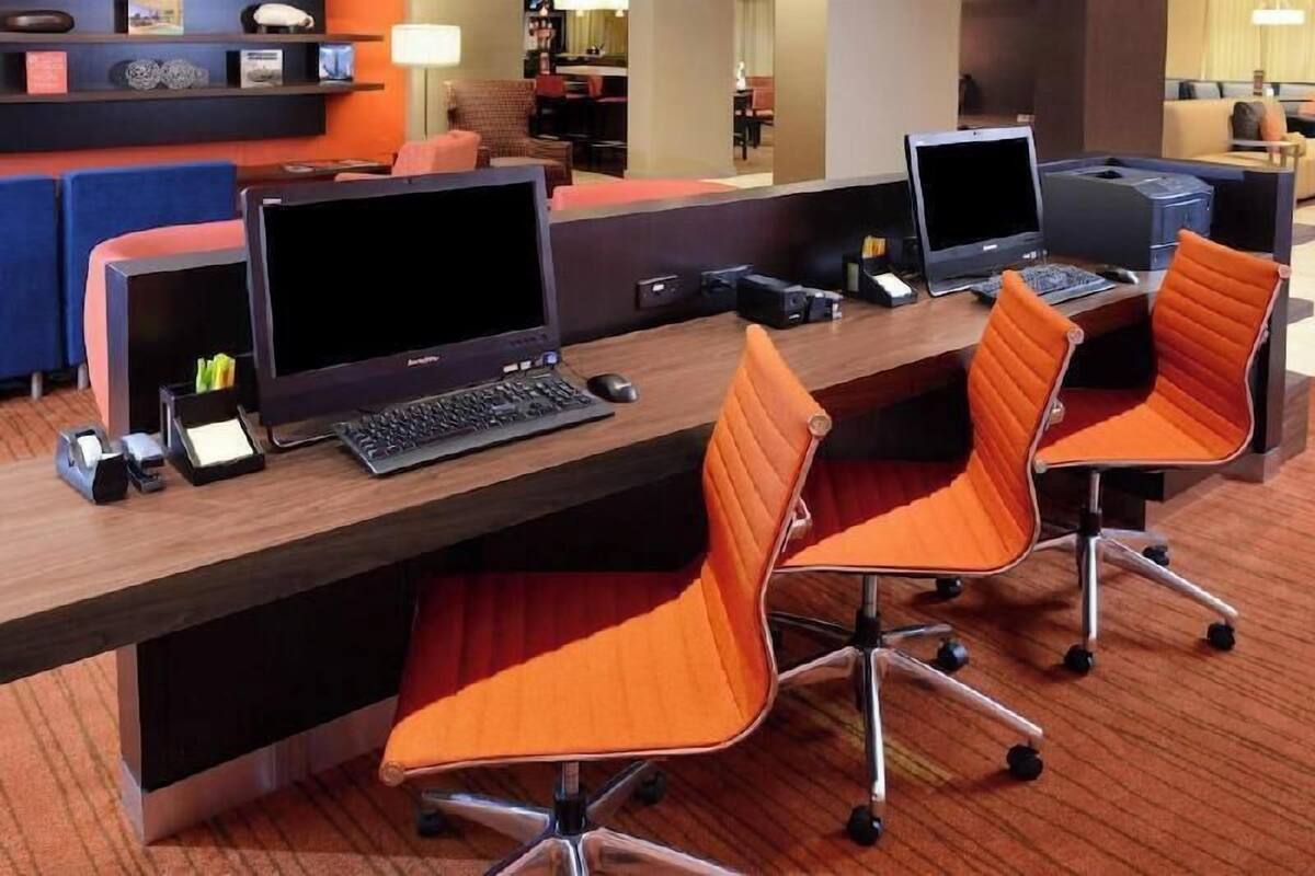 Zona de recepción de hotel con varias estaciones de trabajo de computadora, cada una con una laptop, teclado y ratón.