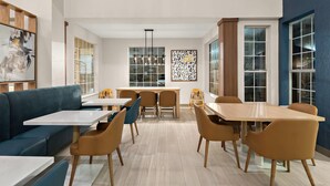 Uma sala de jantar moderna com uma mesa comprida, cadeiras azuis e castanhas, e um sofá azul.