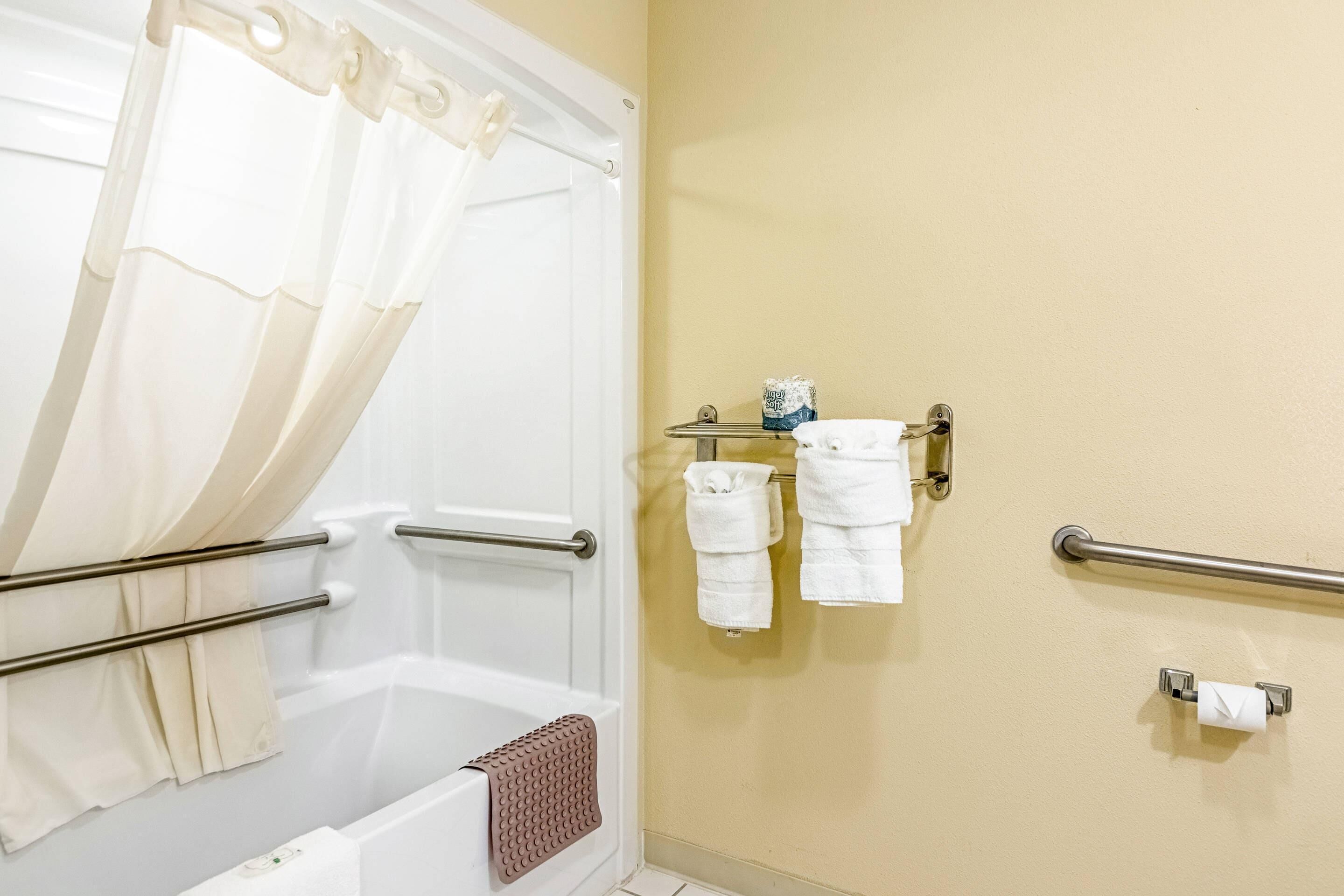 A bathroom with a bathtub, a towel rack, and a toilet paper holder.