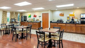A clean, well-lit dining area with wooden tables and chairs, a kitchen counter with appliances, and a view of the dining area through large windows. - Quality Inn Burkeville Hwy 360 & 460 (Burkeville)