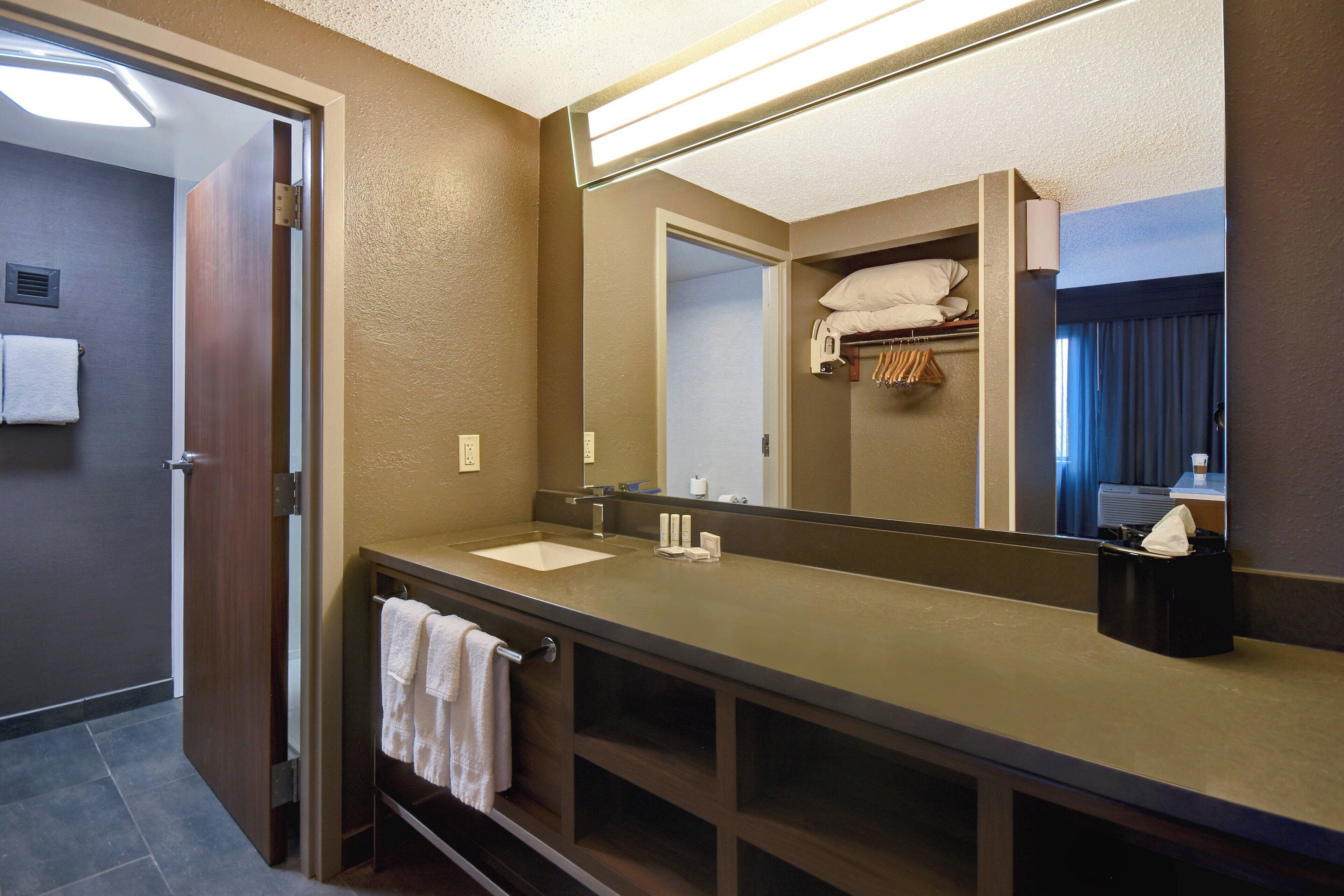 A hotel bathroom with a double sink, a mirror, and a towel rack.