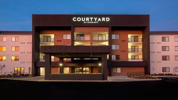 Un hotel Courtyard by Marriott con diseño moderno, varios balcones y una zona de entrada cubierta.