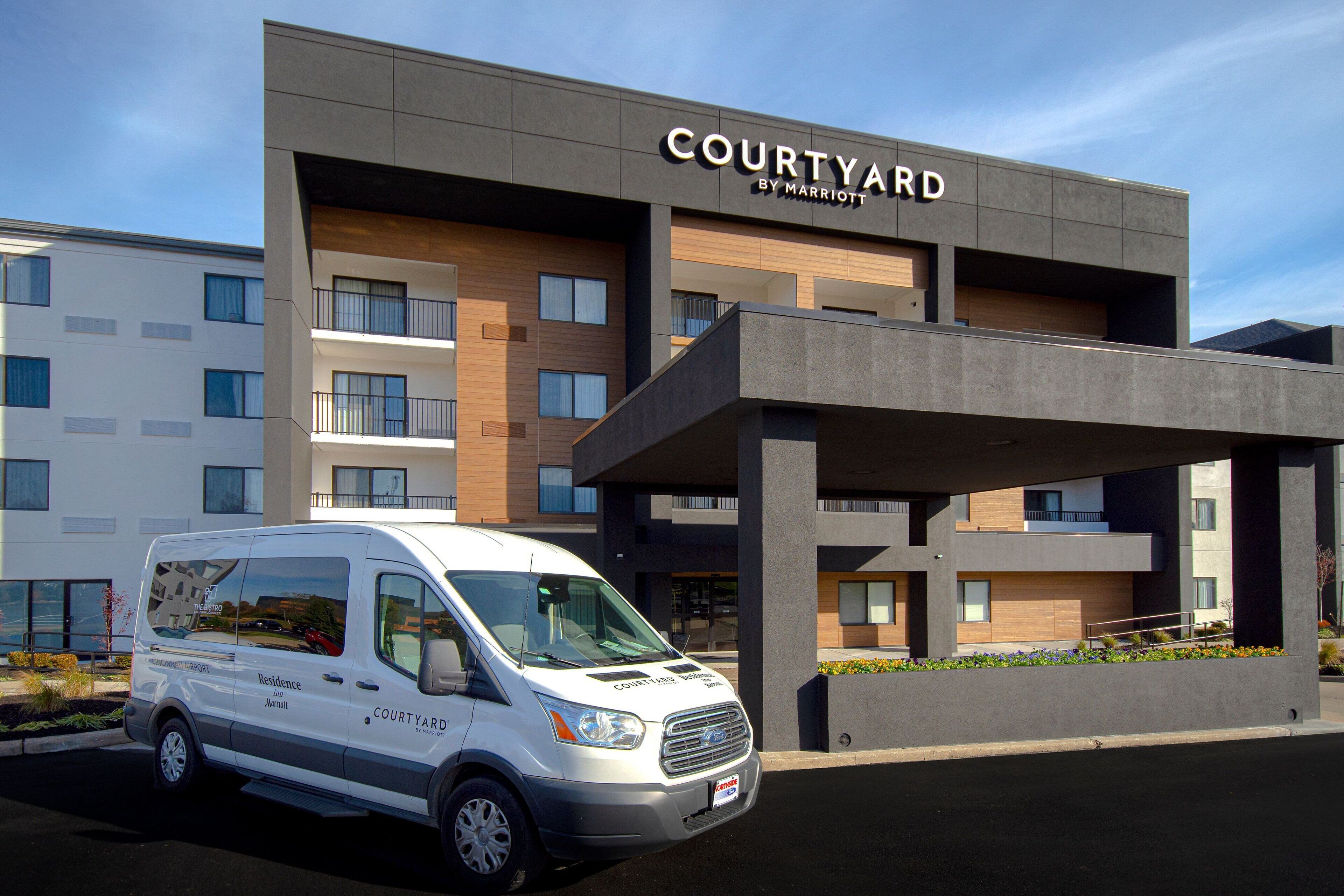 A Courtyard by Marriott hotel with a modern design, featuring a white van parked in front.