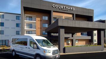 A Courtyard by Marriott hotel with a modern design, featuring a white van parked in front.