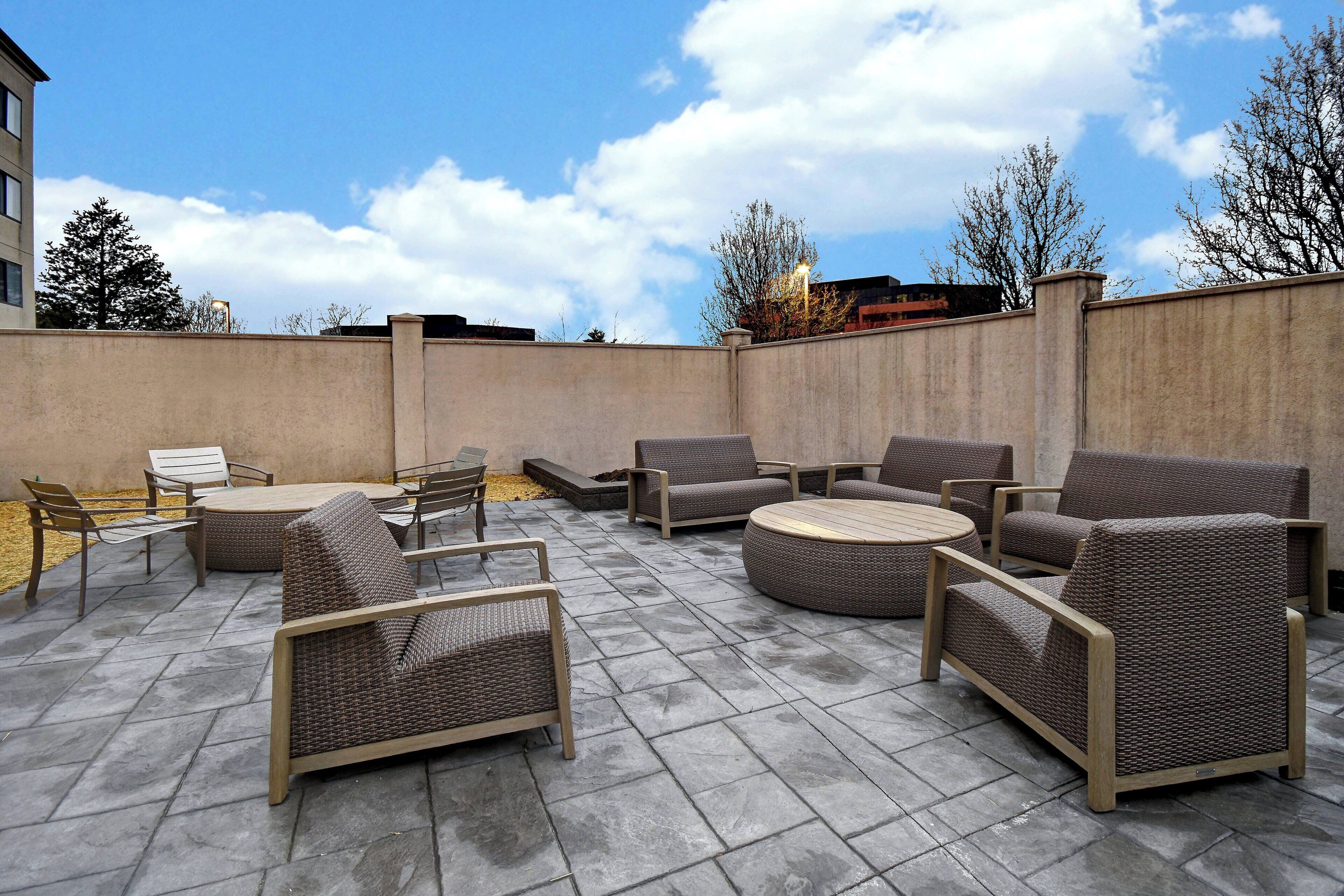 An outdoor patio area with wicker furniture, including sofas and chairs, arranged around a central table.