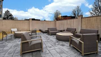 An outdoor patio area with wicker furniture, including sofas and chairs, arranged around a central table.