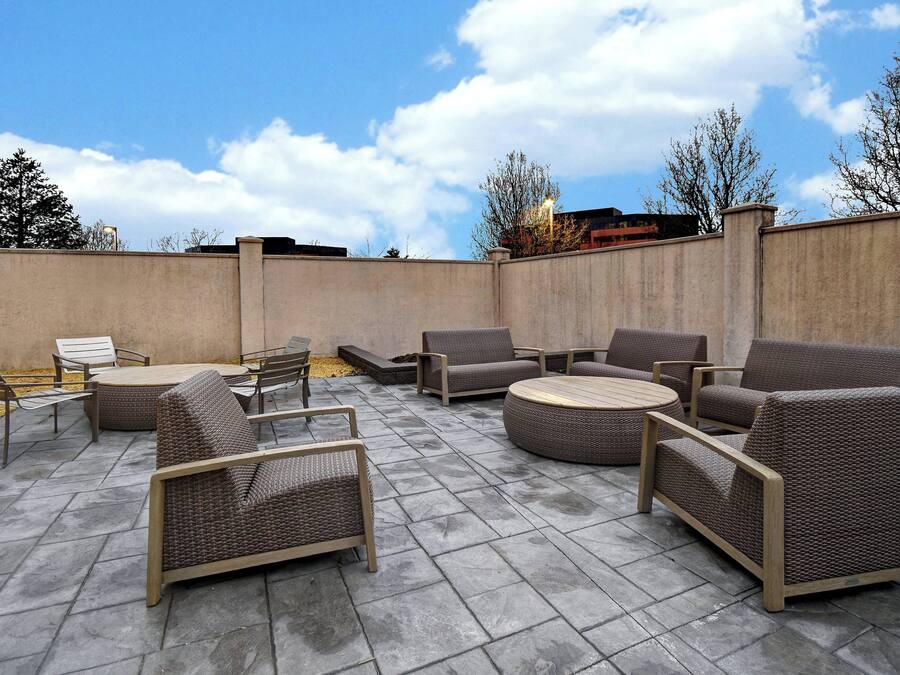 An outdoor patio area with wicker furniture, including sofas and chairs, arranged around a central table.