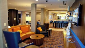 A hotel lobby with seating areas, a bar, and a television. - Courtyard by Marriott Cincinnati Airport (Erlanger)