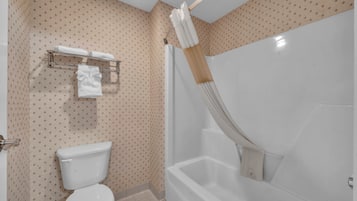 A bathroom with a toilet, a shower with a curtain, and a towel rack with towels.