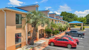 A hotel with a row of rooms, a parking lot, and a covered area.