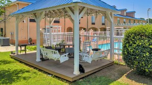 A covered outdoor area with a pool, seating, and a pergola structure. - Gray Inn and Suites (Gray)