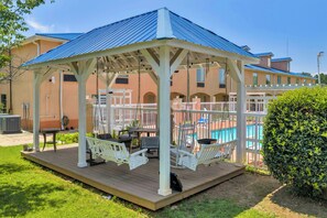 A covered outdoor area with a pool, seating, and a pergola structure. - Gray Inn and Suites (Gray)