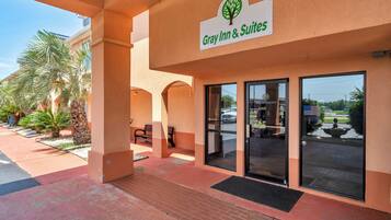 A hotel entrance with a sign reading 'Gray Inn & Suites,' palm trees, and a clear sky.