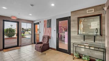 A lobby with a brown leather chair, a glass display case, and an American flag.