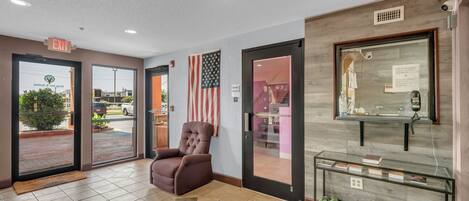 A lobby with a brown leather chair, a glass display case, and an American flag.