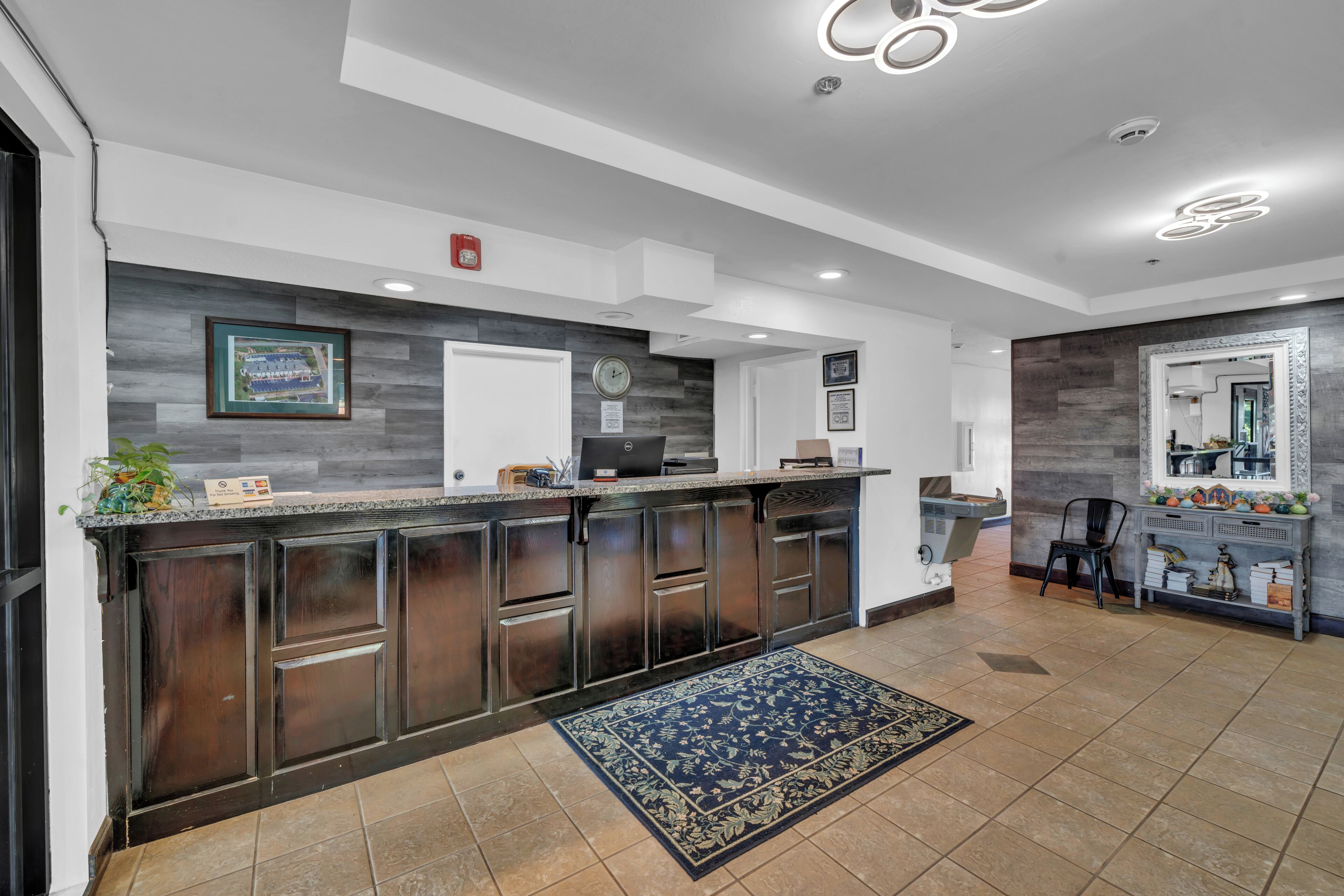 A modern kitchen with dark wood cabinets, a granite countertop, and a blue patterned rug.