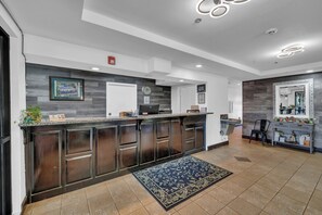 A modern kitchen with dark wood cabinets, a granite countertop, and a blue patterned rug. - Gray Inn and Suites (Gray)