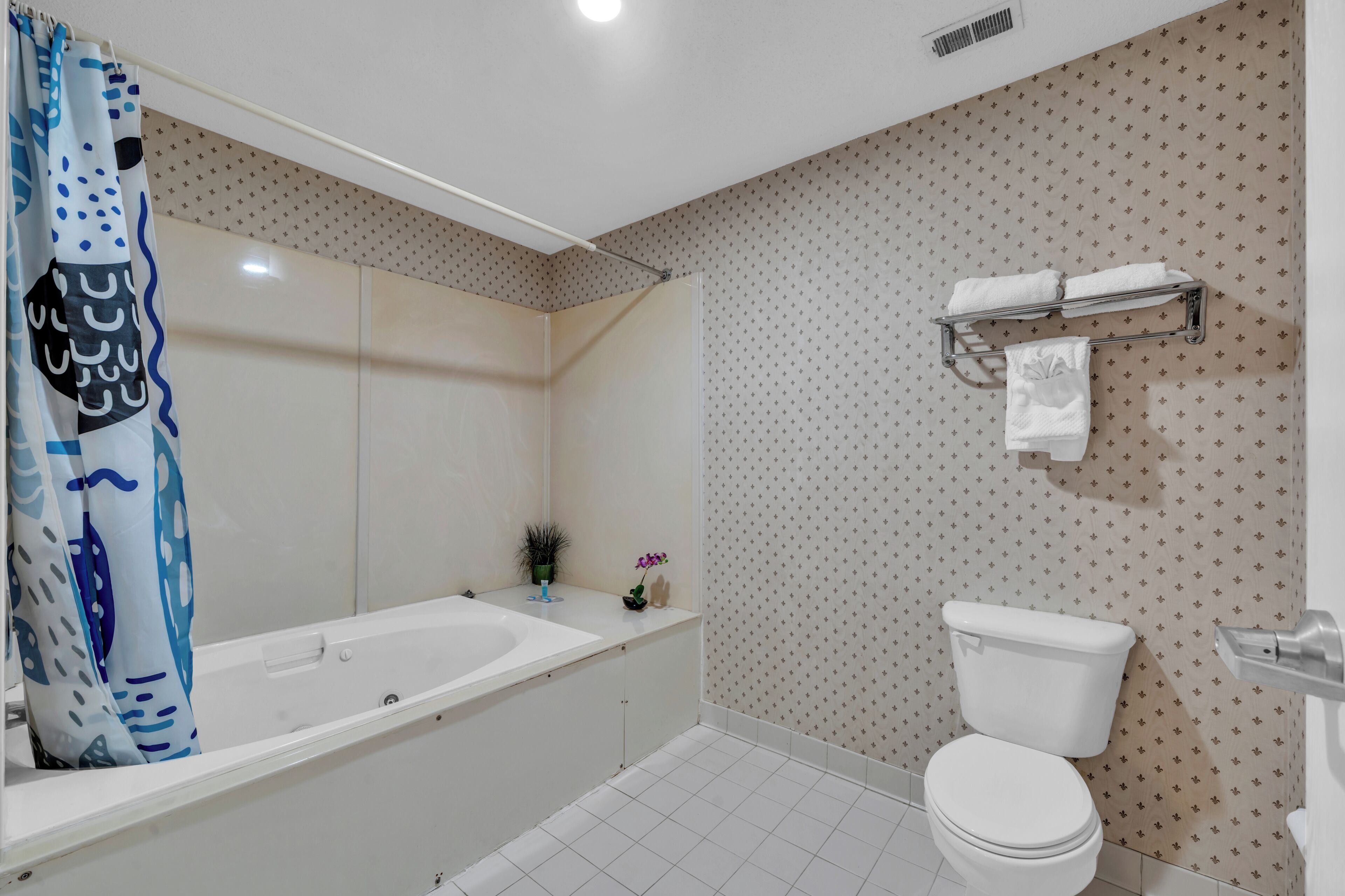 A bathroom with a bathtub, toilet, and shower curtain.