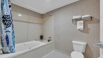 A bathroom with a bathtub, toilet, and shower curtain.