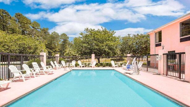 A rectangular swimming pool with white lounge chairs arranged on both sides. - Gray Inn and Suites (Gray)
