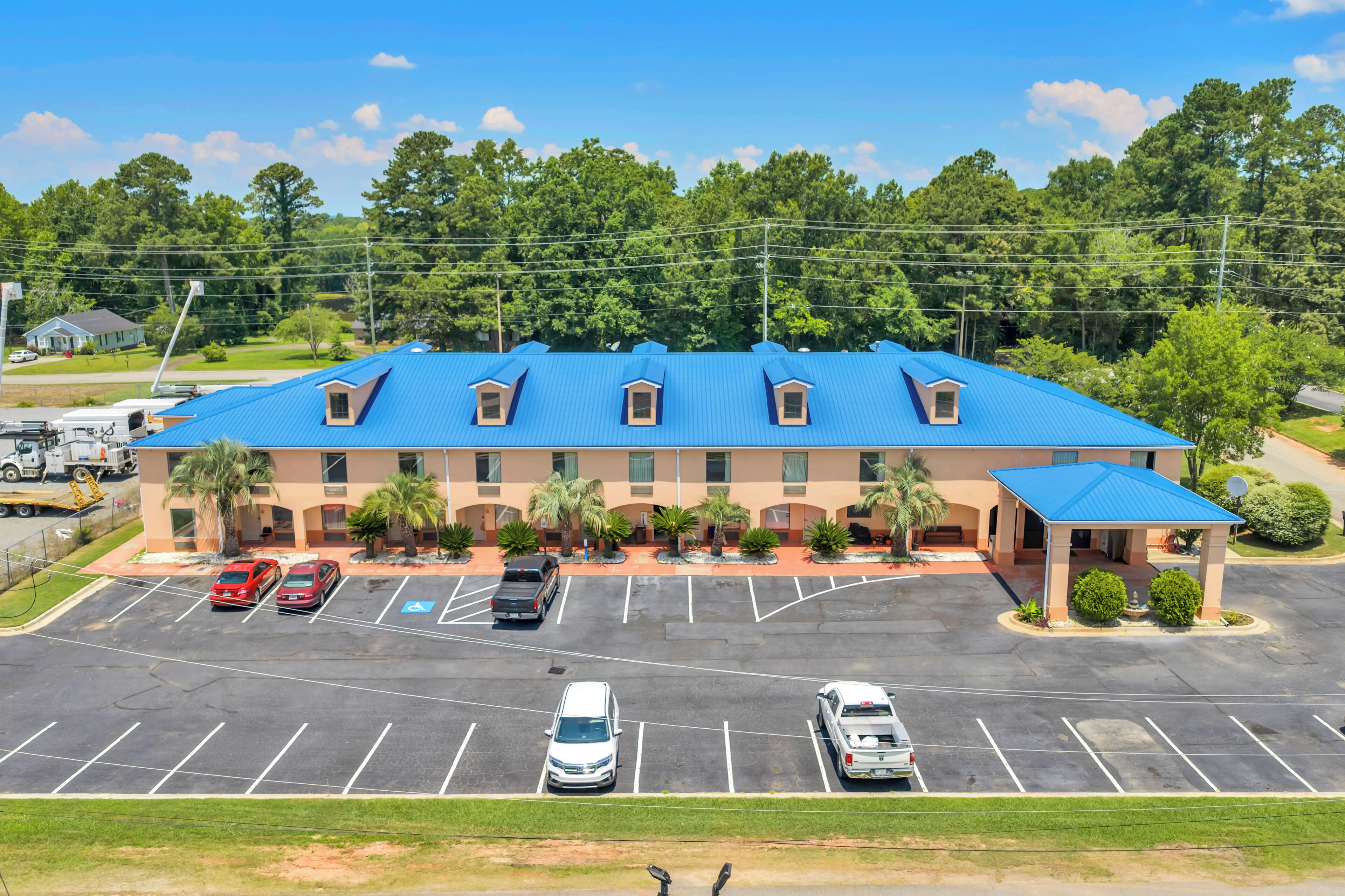 A hotel with a blue roof, multiple parking spaces, and a covered entrance.