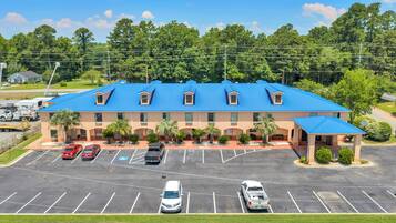 A hotel with a blue roof, multiple parking spaces, and a covered entrance.