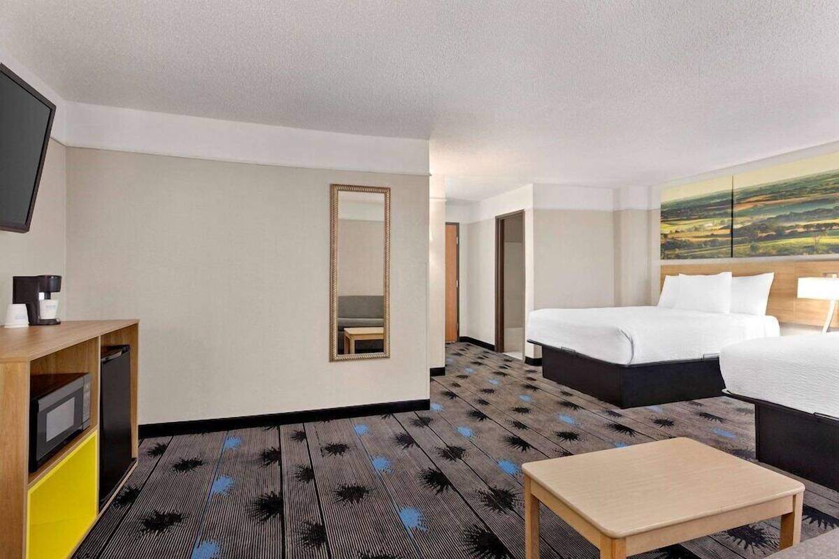 Ein Hotelzimmer mit Bett, Schreibtisch, Spiegel, Fernseher und einem Bild an der Wand.