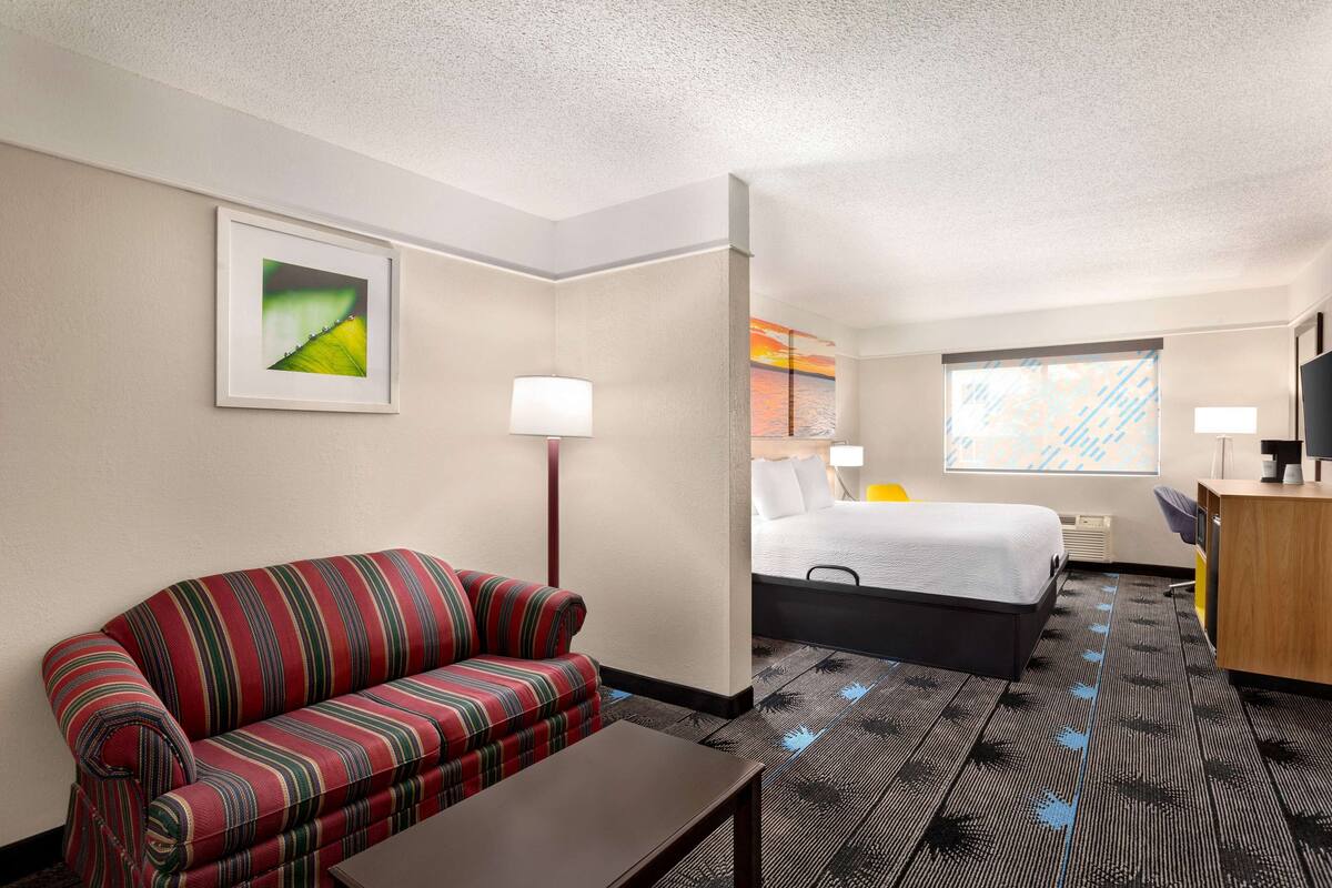 Ein Hotelzimmer mit einem gestreiften Sofa, einem Bett, einem Schreibtisch und einem Fenster mit Blick.