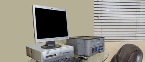 Una configuración de computadora con monitor, teclado e impresora sobre una mesa de vidrio.
