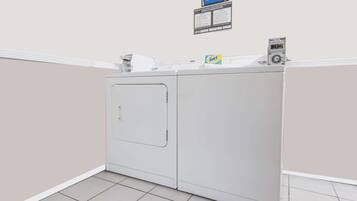 A laundry room with a washing machine and dryer, a sign for guest laundry hours, and a small box of detergent on the dryer.