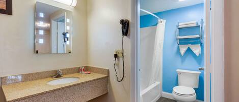 Un baño con lavamanos, espejo, secador de pelo e inodoro.