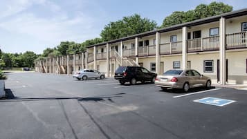 Un motel à plusieurs étages, un parking avec des places réservées aux personnes handicapées et un ciel dégagé.
