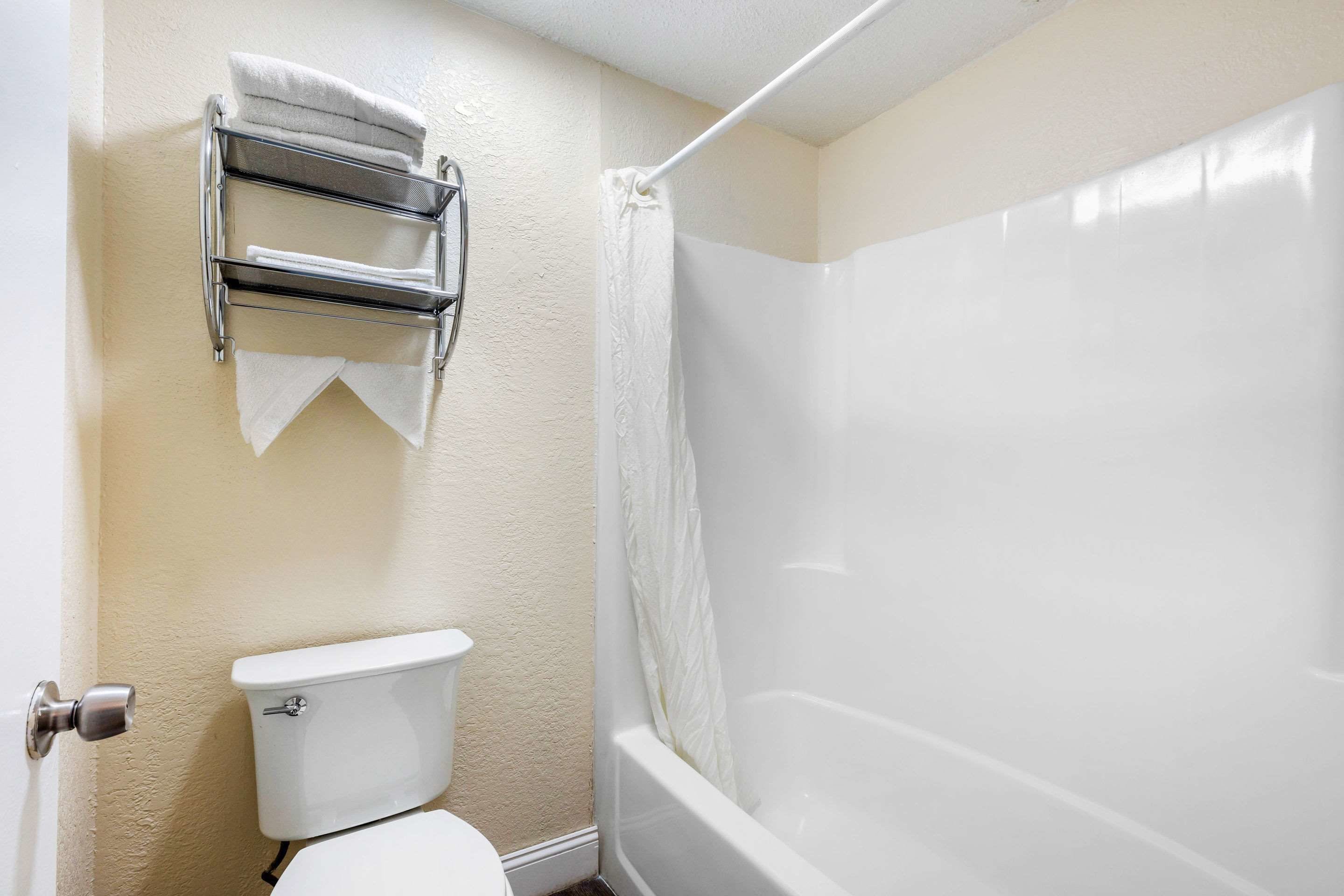 A bathroom with a toilet, a towel rack, and a shower.