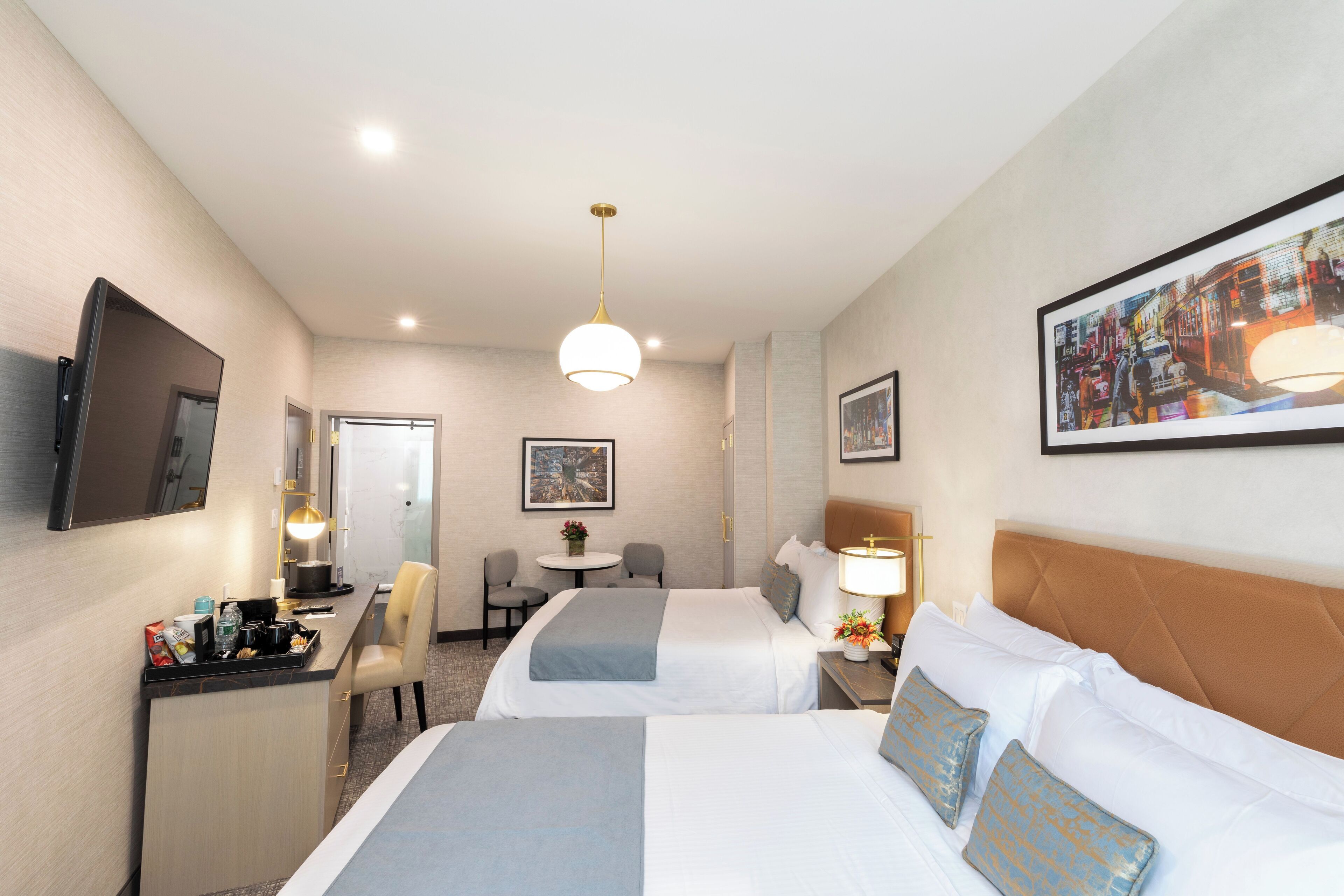Une chambre d’hôtel avec deux lits, un bureau, une chaise, une petite table et un téléviseur.