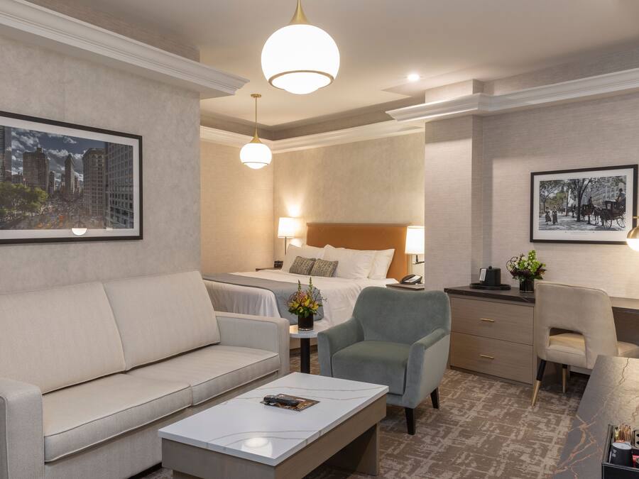 Een hotelkamer met een bank, twee eenpersoonsbedden, een bureau en een stoel.