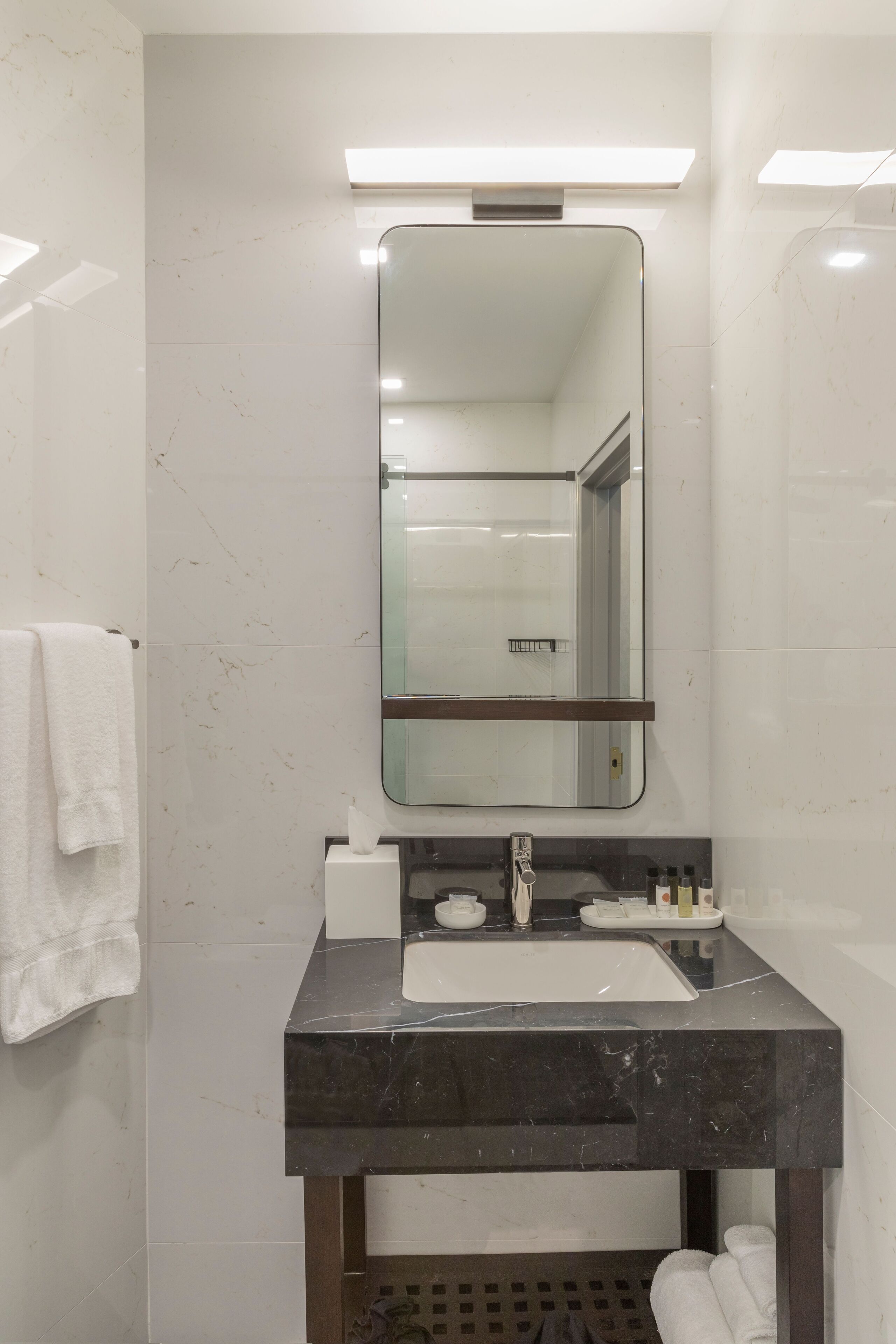 Une salle de bain moderne avec un lavabo en marbre, un grand miroir et un porte-serviettes.