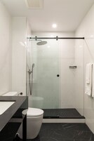 A modern bathroom with a glass-enclosed shower, a white toilet, and a black marble floor.