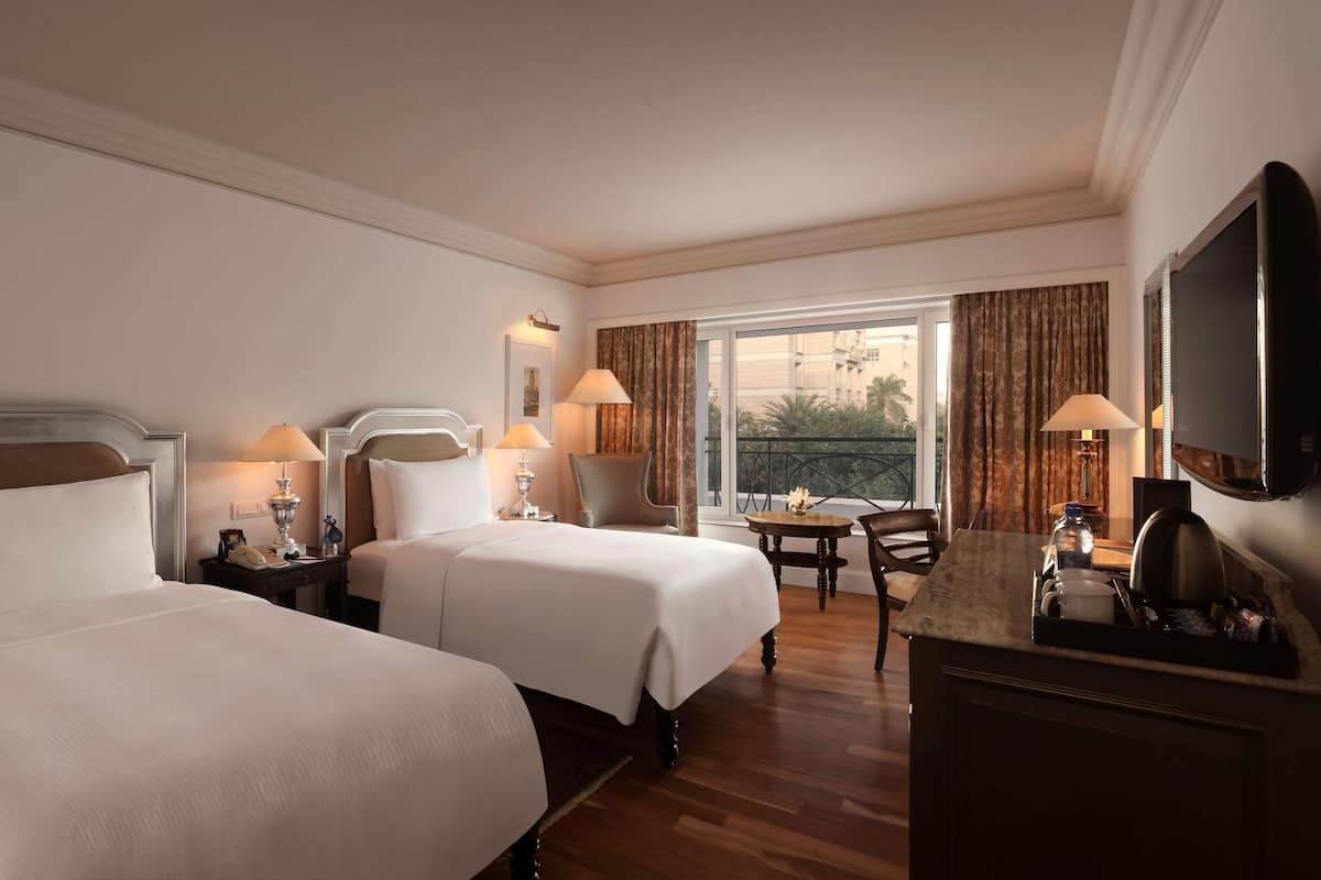 Een hotelkamer met twee bedden, een bureau, een stoel en een televisie.