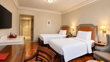 Une chambre d’hôtel avec deux lits, un bureau, une chaise et une table à manger.