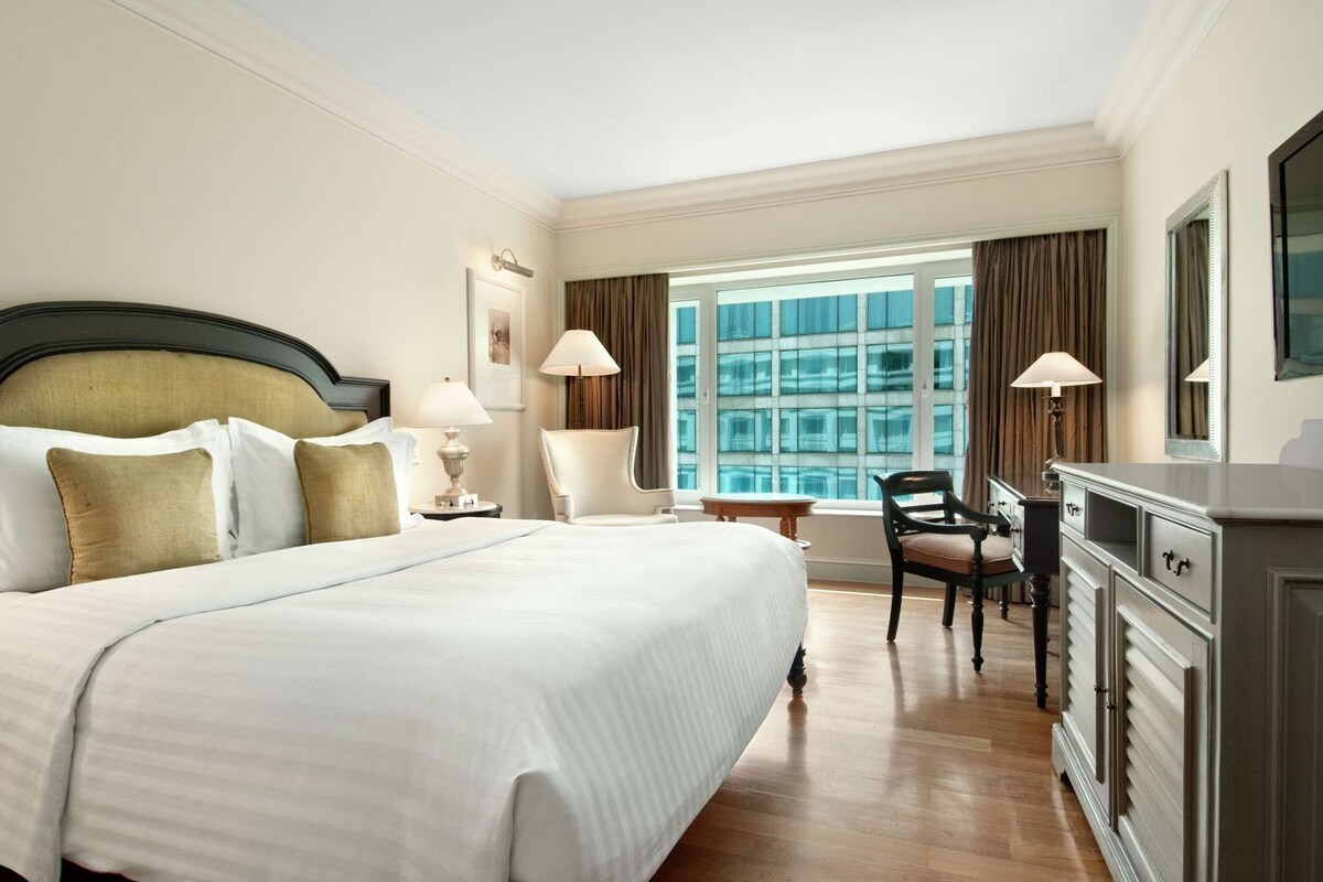 Une chambre d’hôtel avec un grand lit, un bureau, une chaise et une commode.