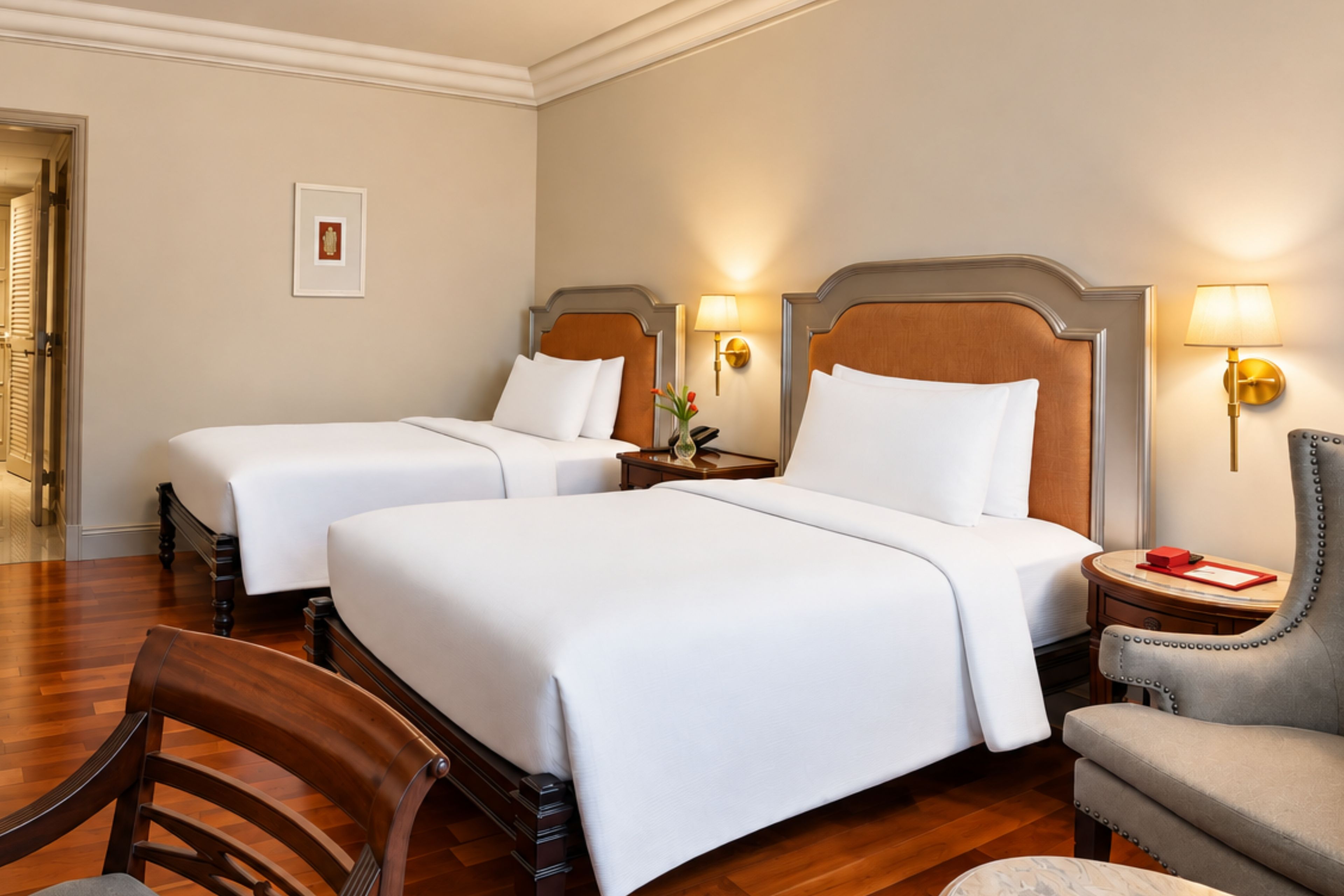 A hotel room with two beds, a wooden chair, a nightstand, and a lamp.