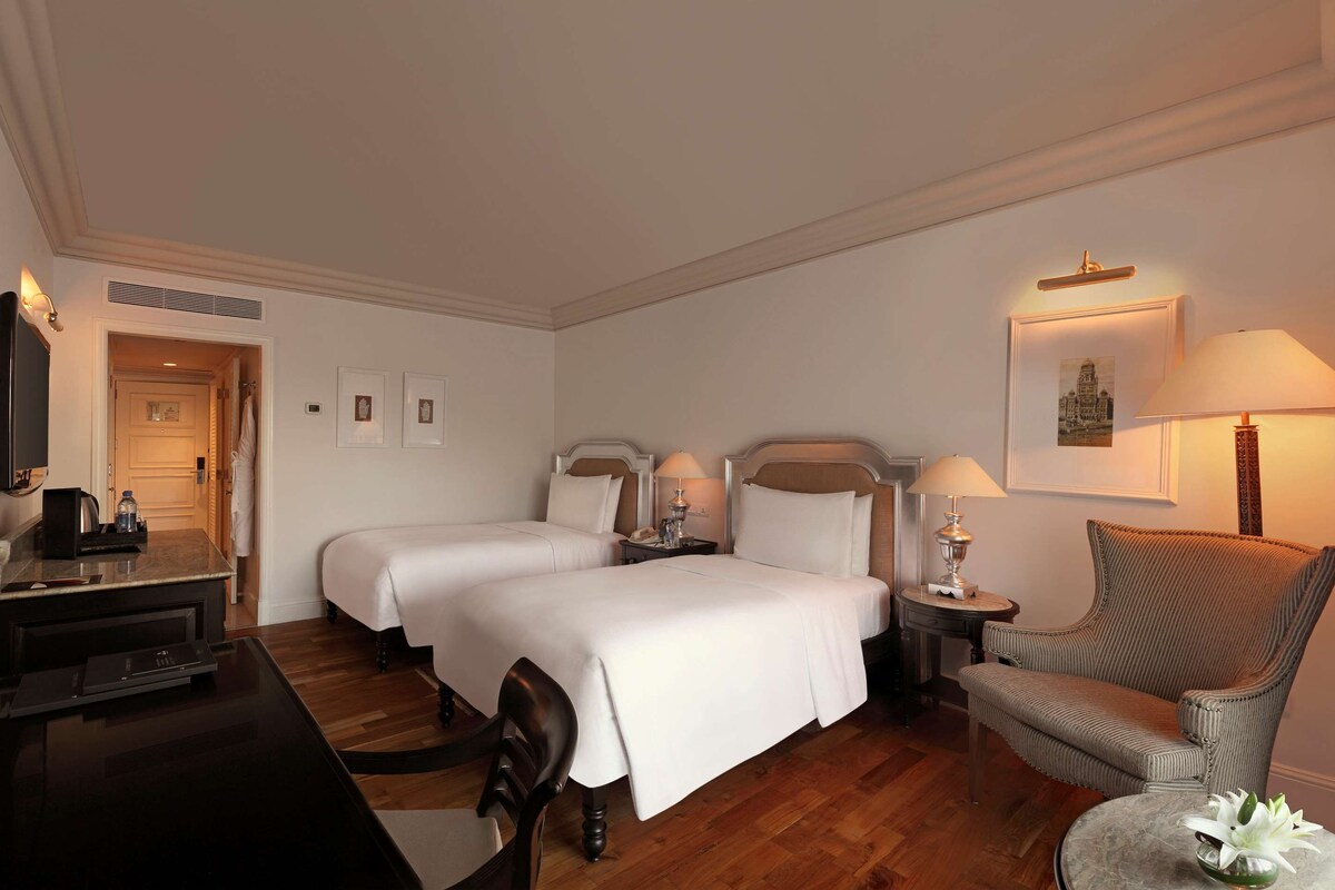 Une chambre d’hôtel avec deux lits, un bureau équipé d’un ordinateur, une chaise, une lampe et un miroir.