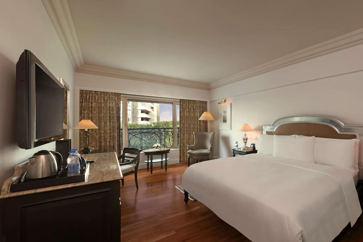 Een hotelkamer met een bed, bureau, stoel, televisie en een balkon met uitzicht.