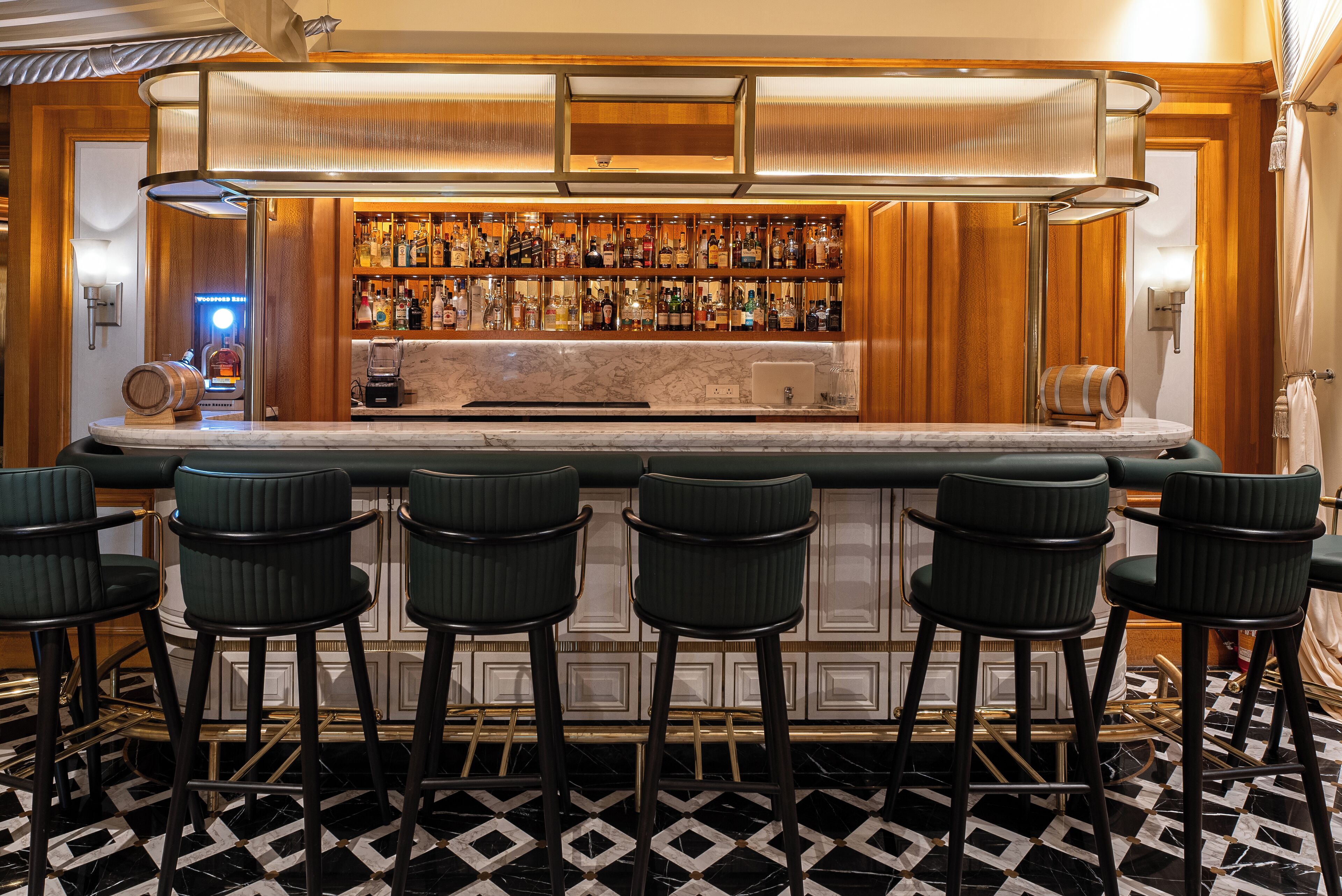 A bar area with a marble countertop, multiple liquor bottles, and bar stools.
