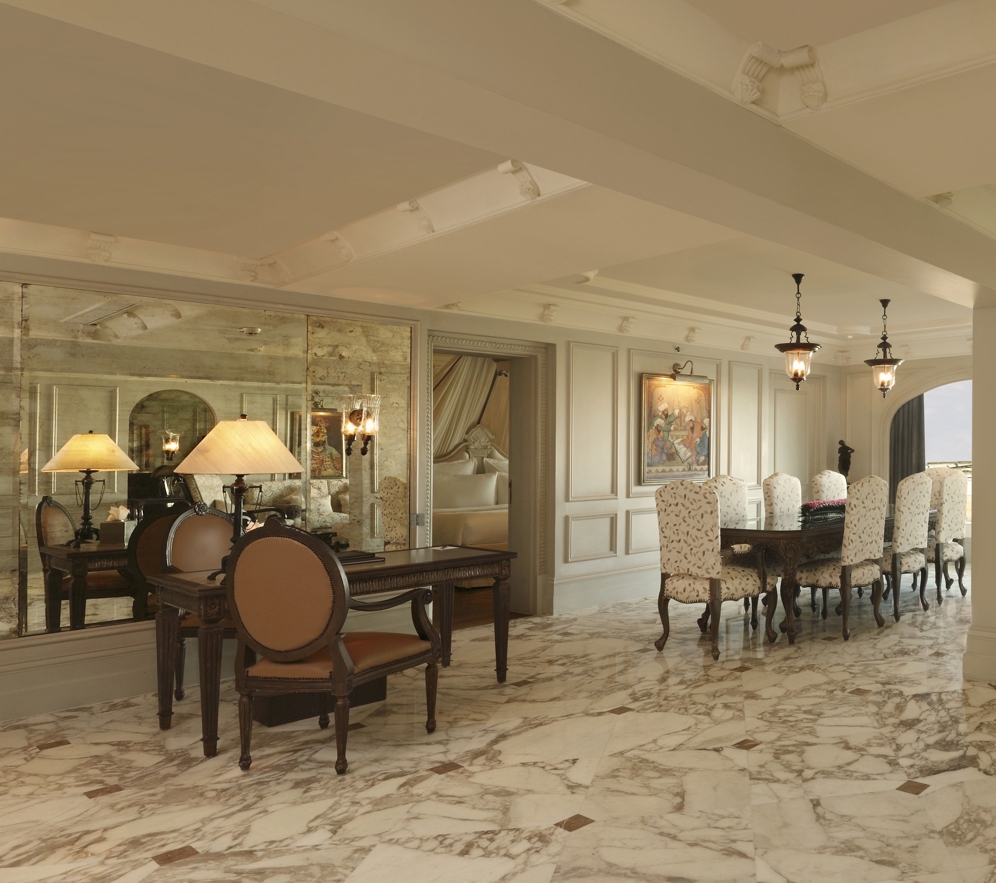 A room with a marble floor, a dining table with chairs, and a large mirror reflecting the room.