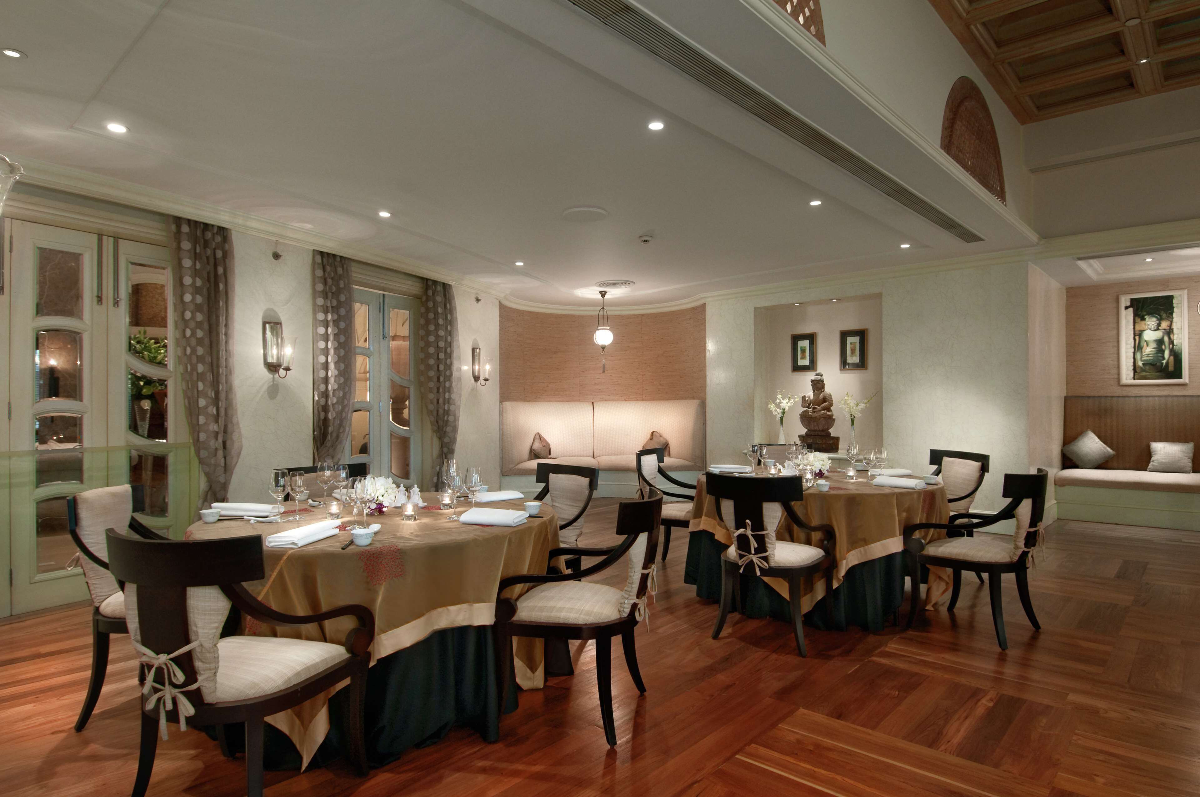 Un comedor formal con varias mesas y sillas, luminarias elegantes y un diseño arquitectónico clásico.