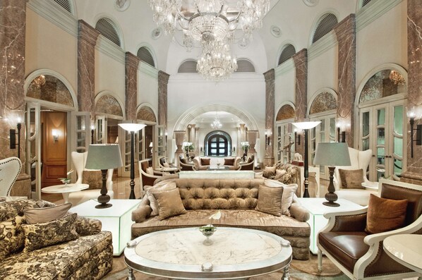 Un hall d’entrée luxueux, agrémenté d’un magnifique lustre, de fauteuils confortables et de sols en marbre.